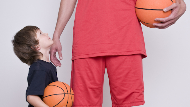A man wearing all red holding a basketball next to a child